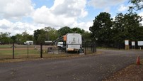 image of RV park with fence and bus parked
