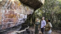 image of three people including Aboriginal guide looking at rock art