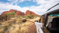image of woman holding hat out window as driving towards red boulders