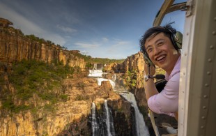 image of man looking out of helicopter over waterfalls