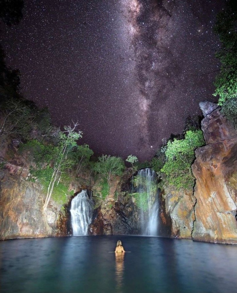 night image of women in waterfalls with stars above