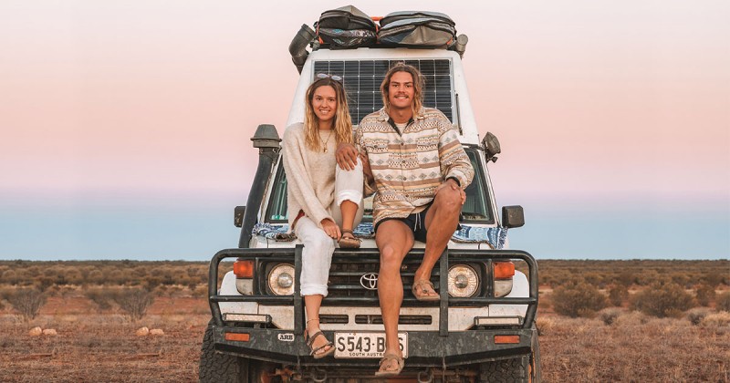 couple sitting on bonnet of 4WD in remote location