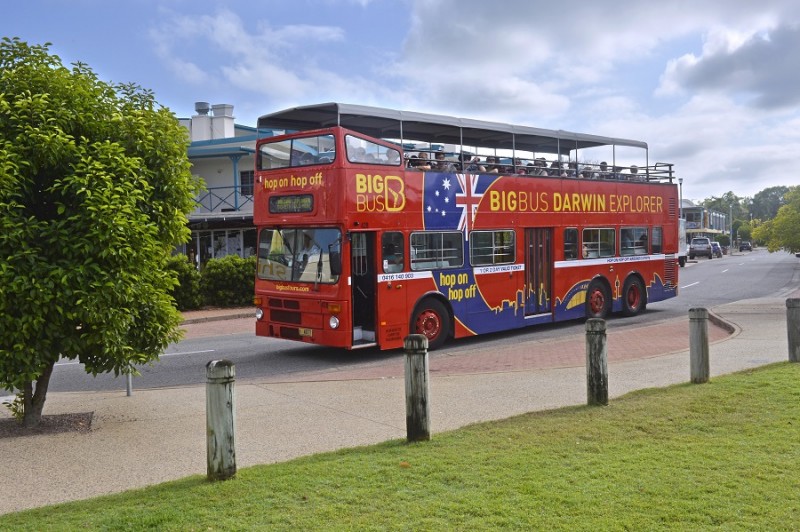 image of red tourist bus with passengers driving down street