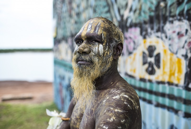 image of Aboriginal man standing in front of buildling painted with art