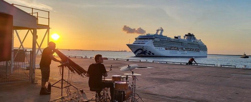 image of two musicians on the dock with a cruise ship in background