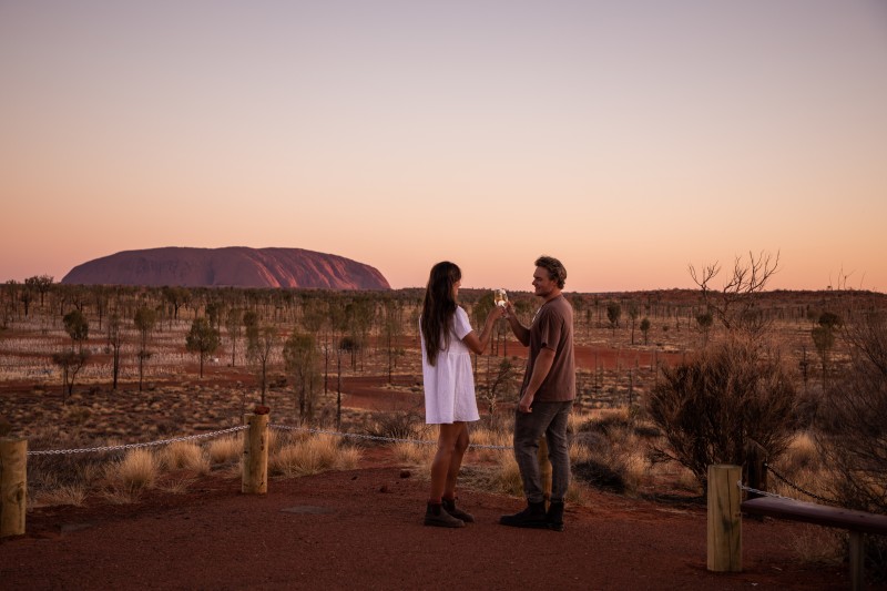 Couple drinking wine and watching sunset over Uluru