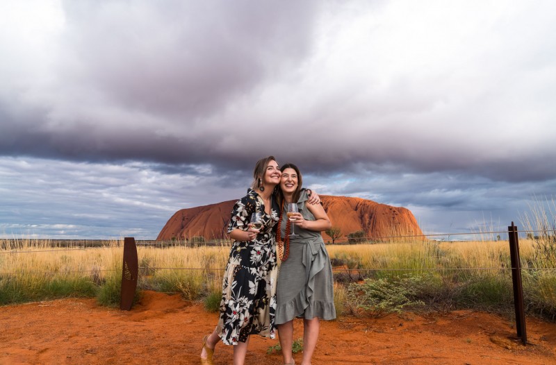 image of women hugging in from of Uluru