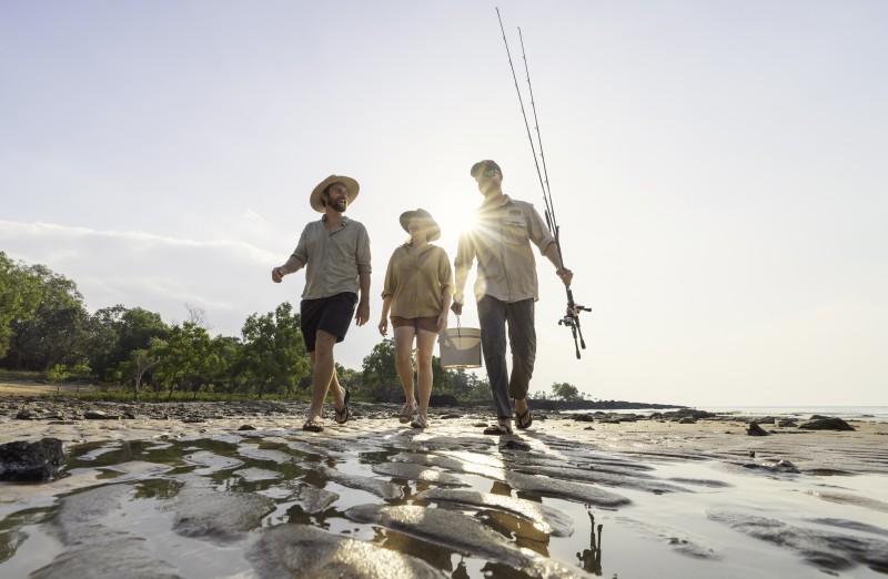 Two tourists with their tour guide walking along a remote beach in Arnhem Land.